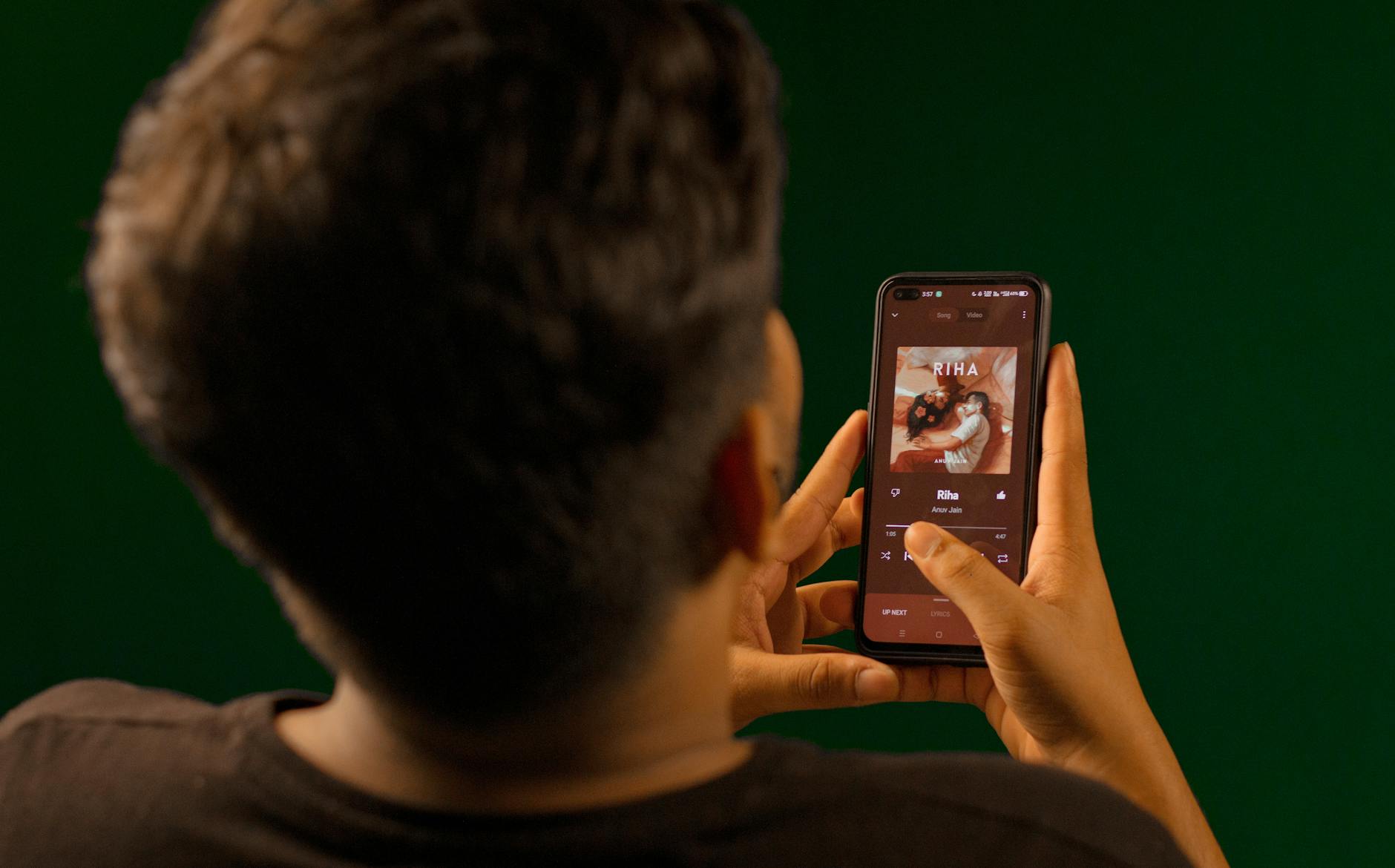 back view of a man playing music on his phone