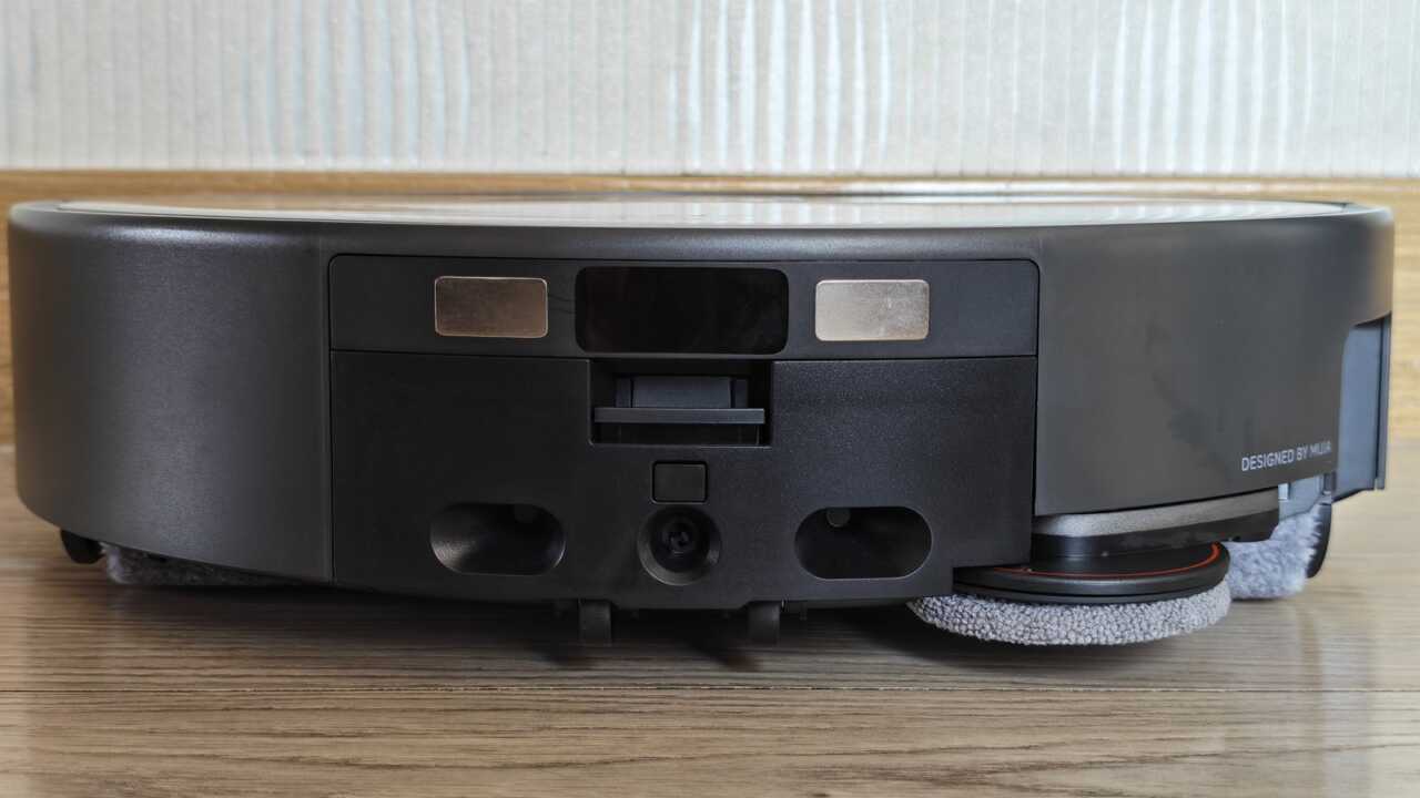 Xiaomi 掃拖機器人 6 Max - 機体の背面：2つの金色の充電接触点、右側には角落ちモップが見え、機体の後部にはDESIGNED BY MIJIAと印刷されています。