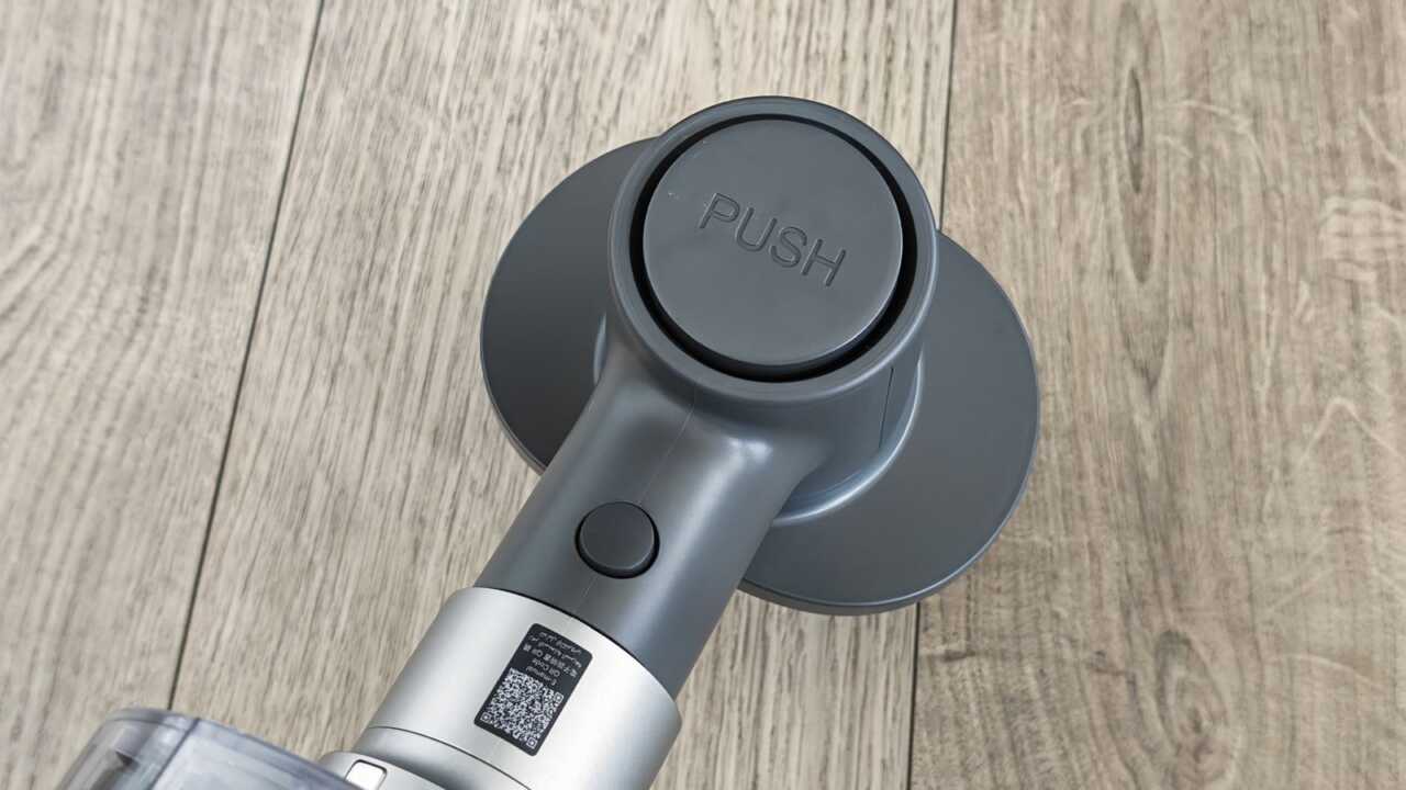 浮毛刷頂部 PUSH 按鍵及連接桿,桿身貼有通用電子說明書 QR 碼