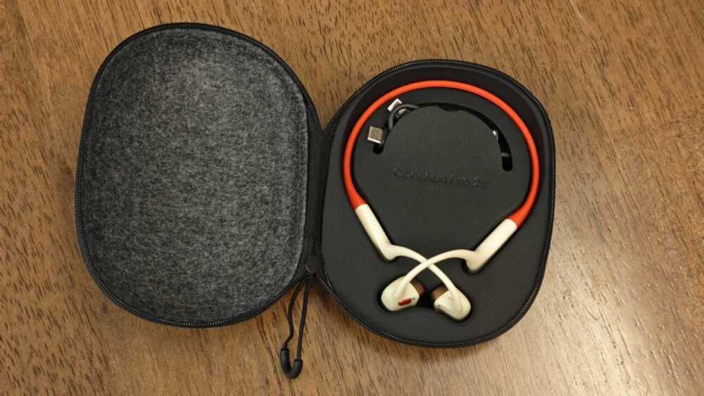 打開收納盒:熔岩橙 OpenRun Pro 2 放喺模塑槽,中間有 USB-C 線